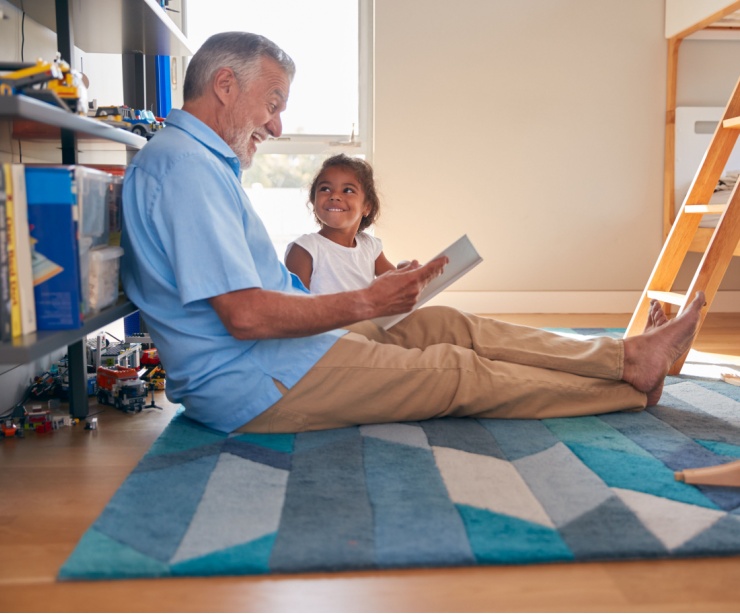 A grandfather reads to his granddaughter.