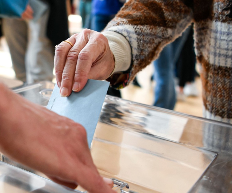 A person putting a ballot paper into a box.