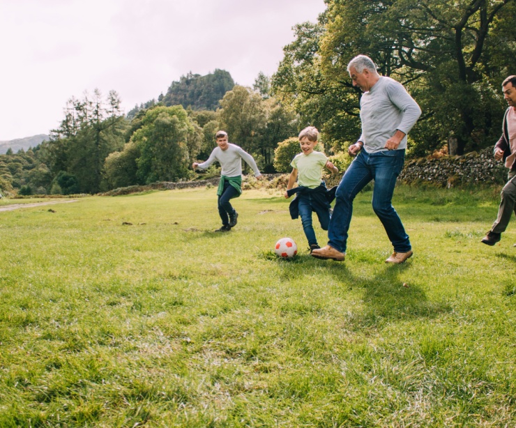 Multi-generational family playing football in a park.