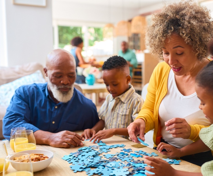 Grandparents doing a jigsaw with their two grandchildren.